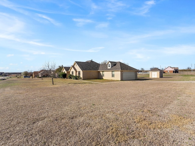 view of yard featuring an attached garage, a storage shed, and driveway