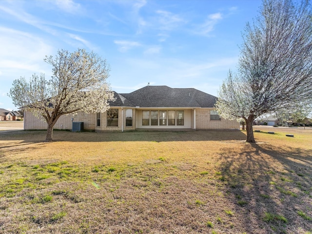 rear view of house with a lawn, brick siding, and central AC