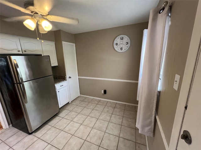 kitchen with light tile patterned flooring, white cabinetry, freestanding refrigerator, and baseboards