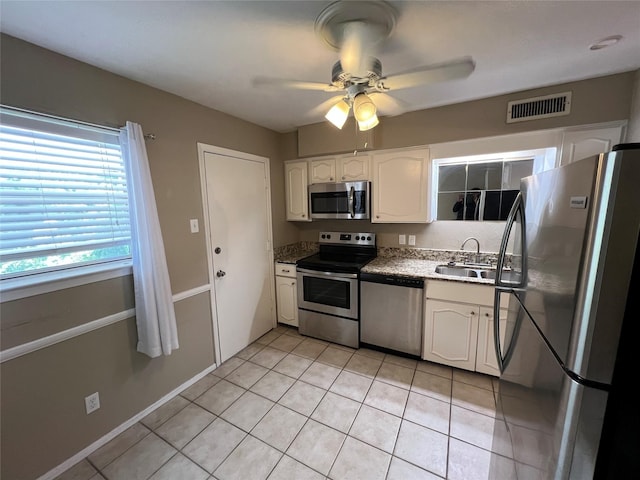 kitchen featuring visible vents, light tile patterned flooring, a sink, stainless steel appliances, and white cabinetry