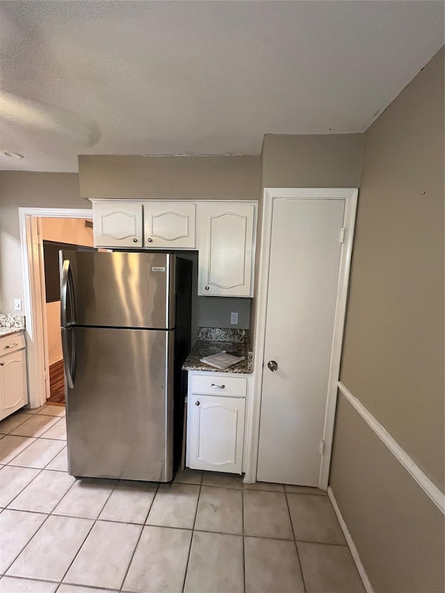 kitchen with white cabinets, light tile patterned flooring, and freestanding refrigerator