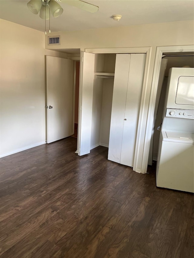 unfurnished bedroom with visible vents, dark wood-type flooring, a closet, and stacked washing maching and dryer