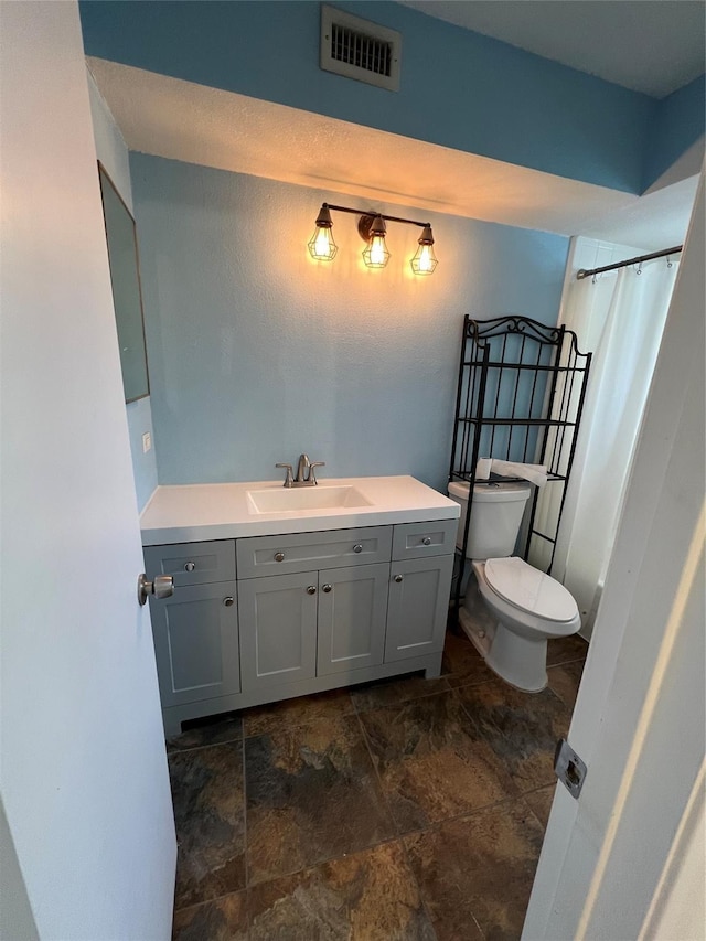 full bathroom with visible vents, toilet, stone finish floor, a shower with shower curtain, and vanity