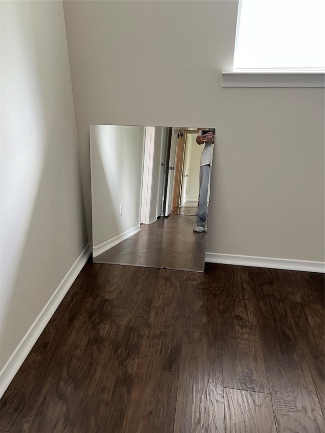 unfurnished room featuring baseboards and dark wood-style flooring