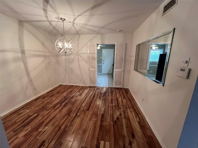 unfurnished dining area featuring visible vents, an inviting chandelier, baseboards, and wood finished floors