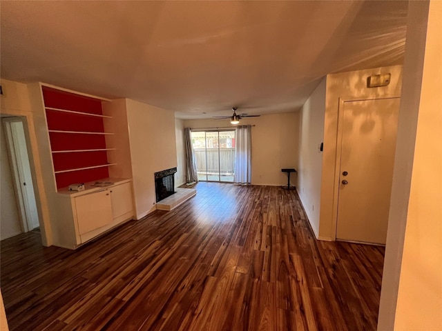 unfurnished living room with a ceiling fan, a fireplace with raised hearth, and dark wood-style flooring