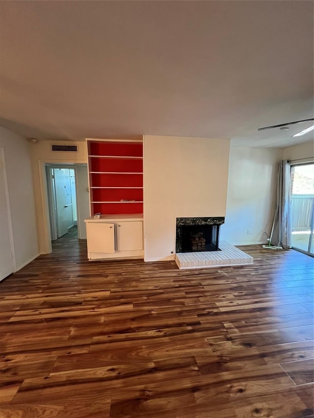 unfurnished living room featuring dark wood finished floors, visible vents, and a fireplace