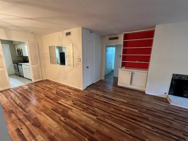 unfurnished living room featuring visible vents, wood finished floors, and a fireplace