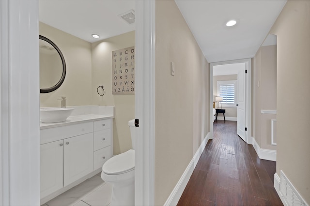 bathroom with visible vents, toilet, baseboards, and hardwood / wood-style flooring