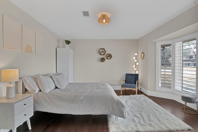 bedroom with dark wood-style floors, visible vents, multiple windows, and baseboards