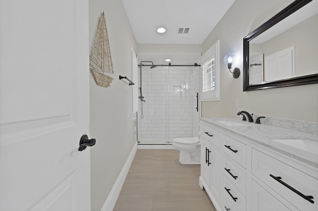 bathroom featuring visible vents, baseboards, toilet, a stall shower, and a sink