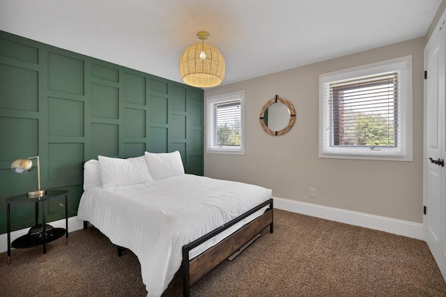 bedroom featuring baseboards and dark carpet