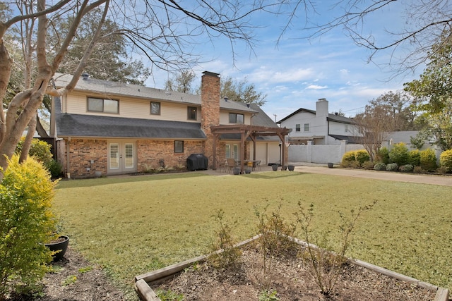 rear view of property featuring brick siding, fence, french doors, a yard, and a pergola