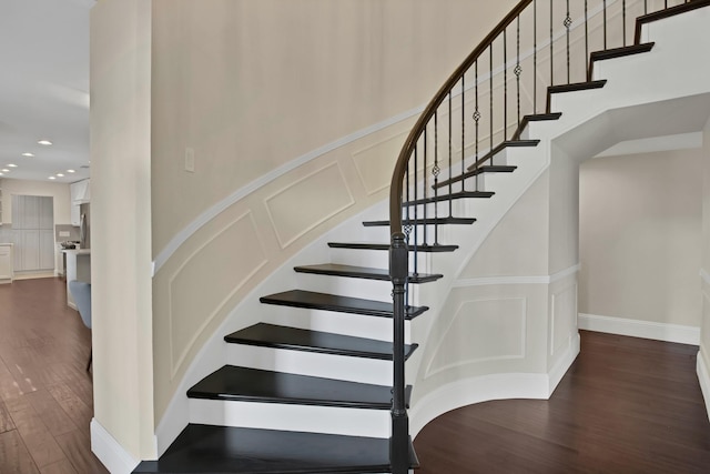 stairs featuring a decorative wall, recessed lighting, and wood finished floors