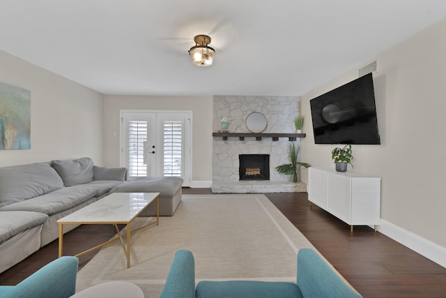 living room with wood finished floors, visible vents, baseboards, a fireplace, and french doors