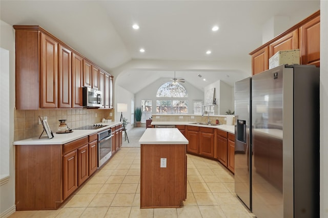 kitchen with tasteful backsplash, vaulted ceiling, appliances with stainless steel finishes, a peninsula, and a sink