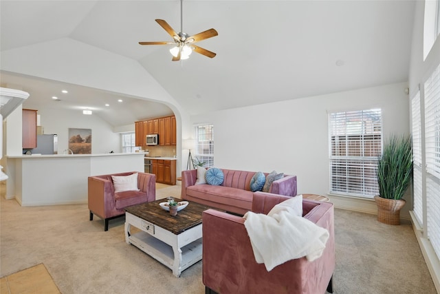 living area featuring arched walkways, light colored carpet, ceiling fan, and high vaulted ceiling