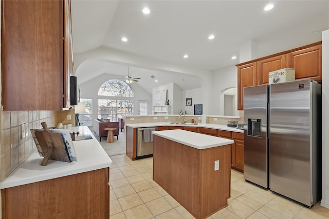 kitchen with light countertops, decorative backsplash, appliances with stainless steel finishes, a peninsula, and a sink