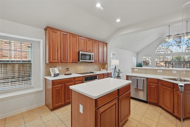 kitchen featuring backsplash, a kitchen island, light countertops, lofted ceiling, and appliances with stainless steel finishes