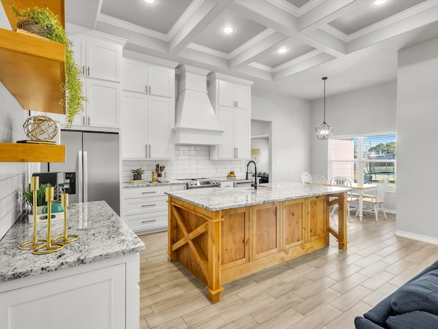 kitchen featuring premium range hood, beamed ceiling, decorative backsplash, appliances with stainless steel finishes, and a sink