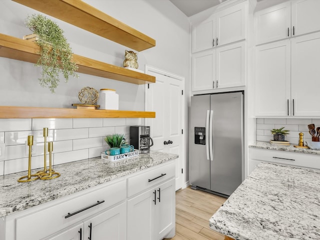 kitchen featuring tasteful backsplash, white cabinets, stainless steel refrigerator with ice dispenser, and open shelves