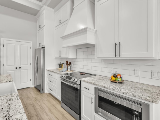 kitchen featuring custom range hood, white cabinets, backsplash, and stainless steel appliances