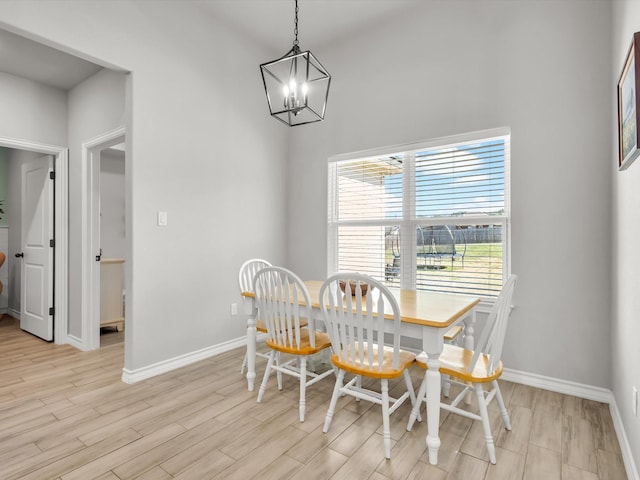 dining area featuring baseboards, light wood-style floors, and a chandelier