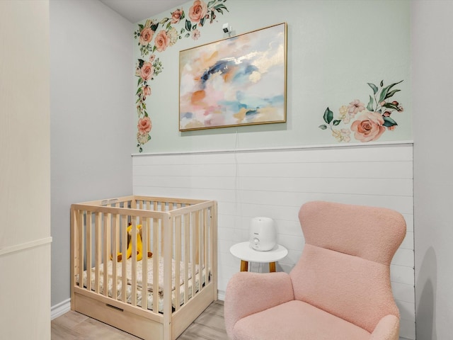 bedroom featuring a wainscoted wall and a crib