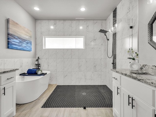 bathroom featuring tile walls, walk in shower, recessed lighting, a soaking tub, and vanity