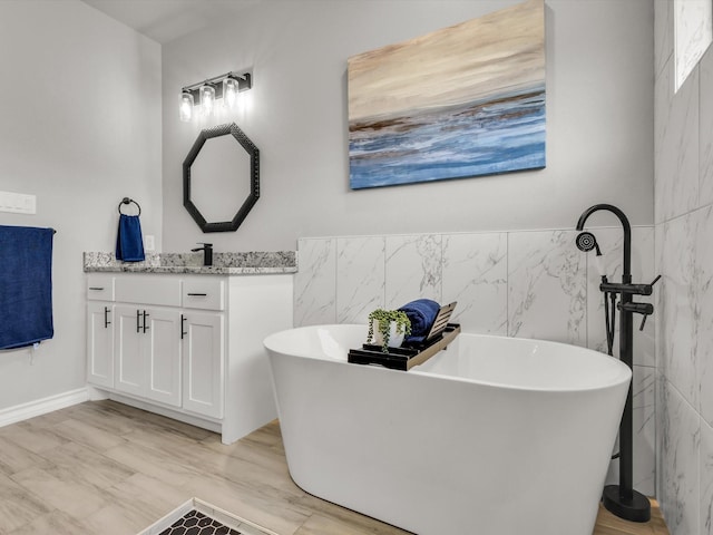 full bathroom with a freestanding bath, tile walls, and vanity