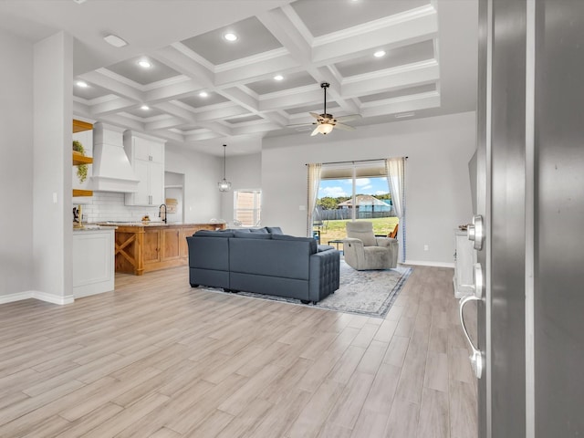 living area featuring light wood-type flooring, beamed ceiling, coffered ceiling, recessed lighting, and ceiling fan