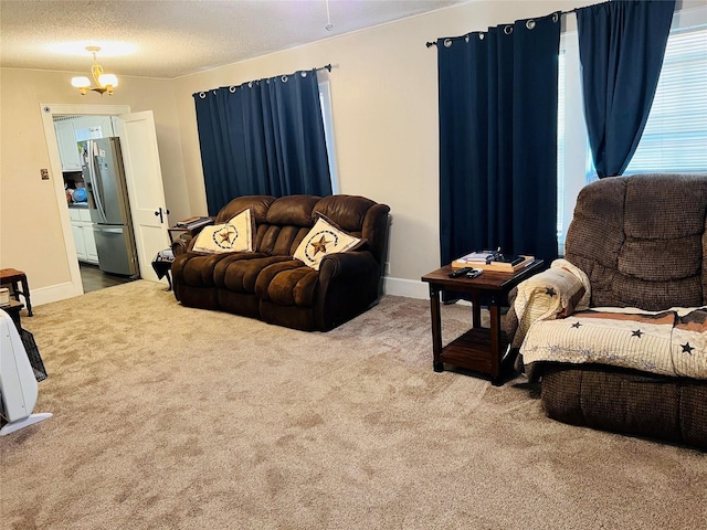 carpeted living area featuring a notable chandelier, baseboards, and a textured ceiling