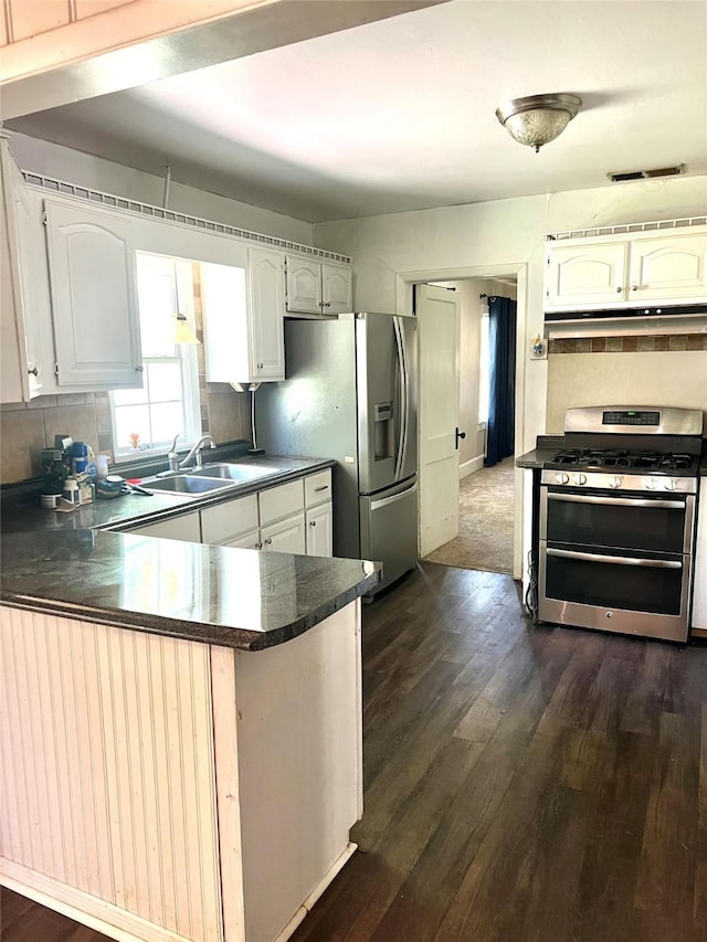 7155 Farm Rd Unit 1499, Sumner, TX 75486 - kitchen with a sink, appliances with stainless steel finishes, dark countertops, dark wood-style flooring, and a peninsula