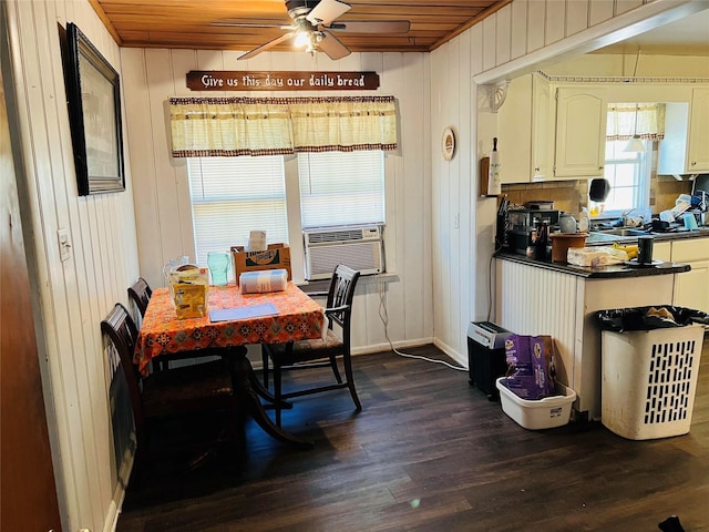 dining room with wooden walls, cooling unit, a ceiling fan, dark wood-style floors, and baseboards