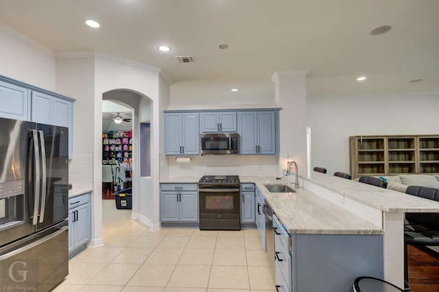 kitchen featuring ornamental molding, a sink, stainless steel appliances, a peninsula, and light stone countertops