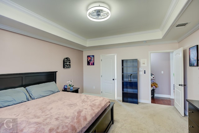 bedroom with a tray ceiling, visible vents, light carpet, and ornamental molding