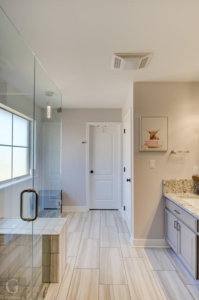 bathroom with visible vents, a stall shower, vanity, and baseboards