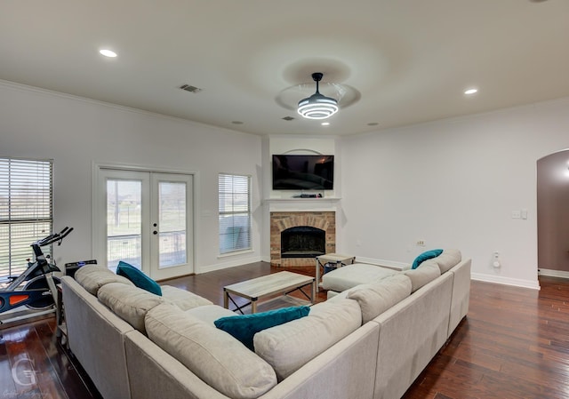 living room featuring visible vents, baseboards, a fireplace, arched walkways, and dark wood-style flooring