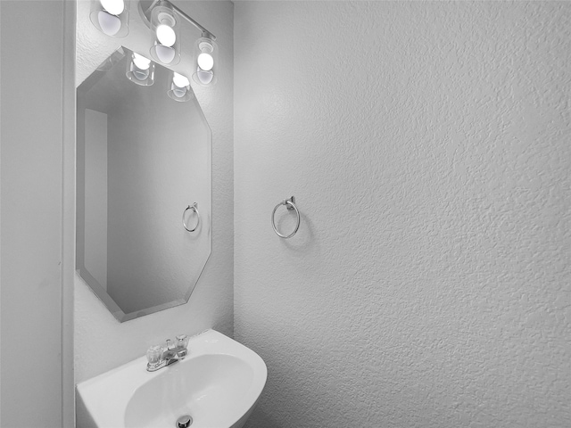 bathroom featuring a textured wall and a sink