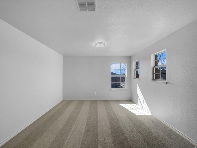 spare room with visible vents, a textured ceiling, baseboards, and carpet floors