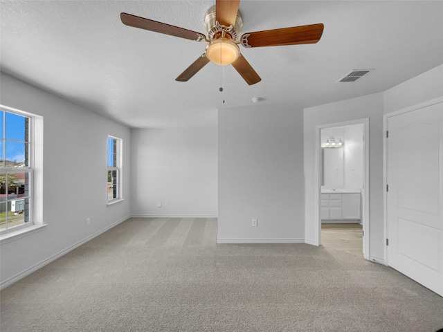 spare room with visible vents, light carpet, a textured ceiling, baseboards, and ceiling fan