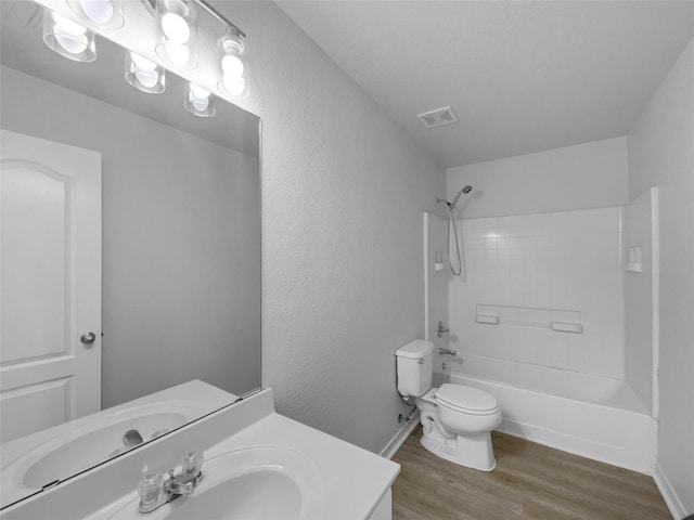 bathroom featuring vanity, wood finished floors, visible vents, bathing tub / shower combination, and toilet