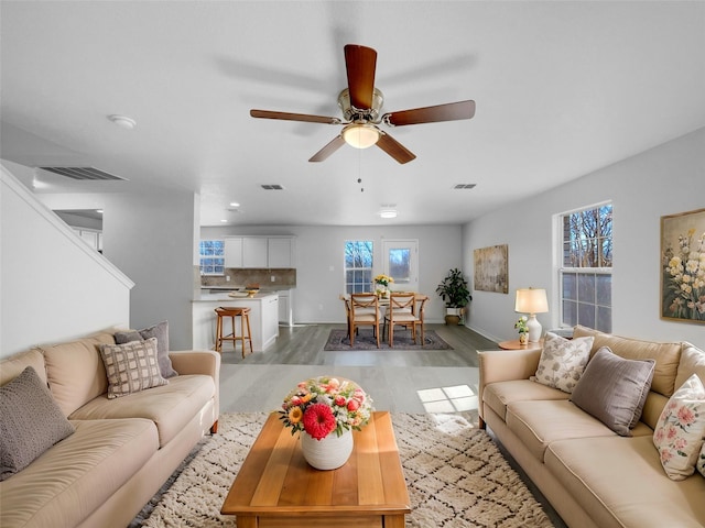 living area with visible vents, wood finished floors, and a ceiling fan