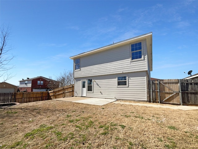 rear view of property featuring a patio, a fenced backyard, and a gate