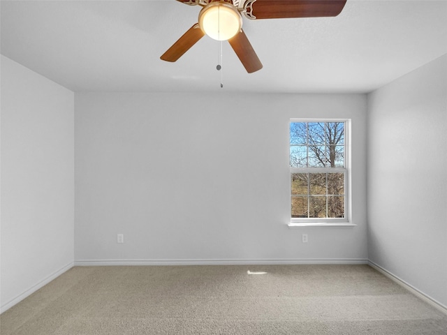 spare room featuring light carpet, a ceiling fan, and baseboards