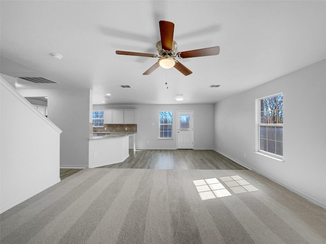 unfurnished living room with baseboards, wood finished floors, visible vents, and ceiling fan