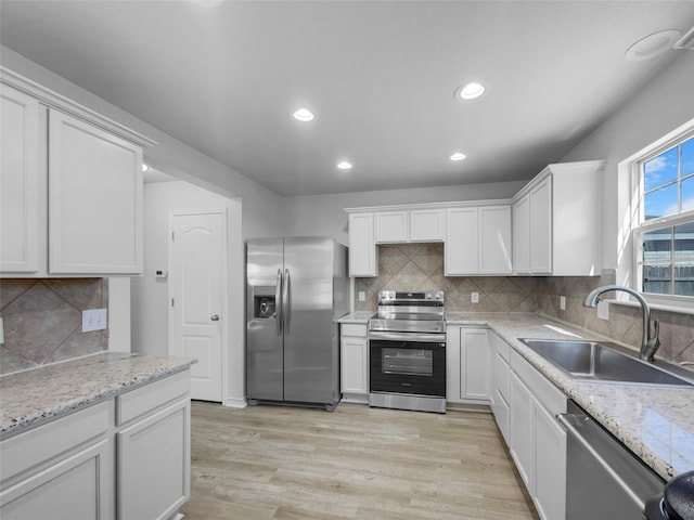 kitchen featuring recessed lighting, a sink, stainless steel appliances, white cabinets, and light wood-type flooring