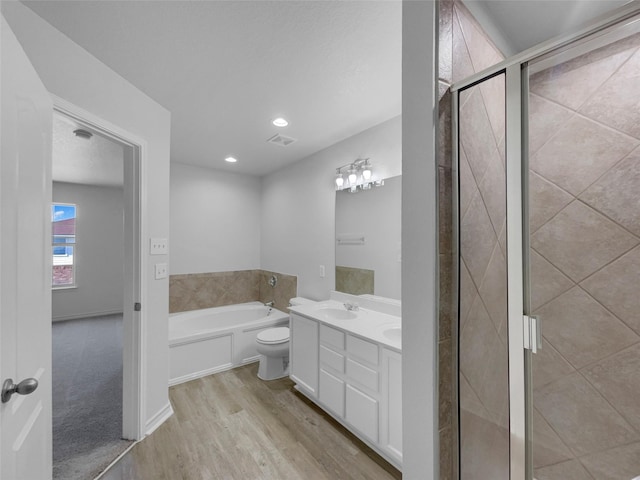 full bathroom with wood finished floors, double vanity, a stall shower, a sink, and a garden tub