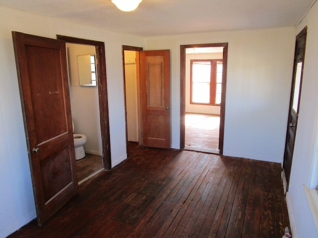 unfurnished bedroom with dark wood-type flooring and baseboards