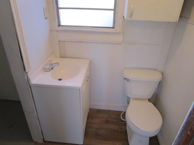 bathroom featuring baseboards, toilet, wood finished floors, and vanity